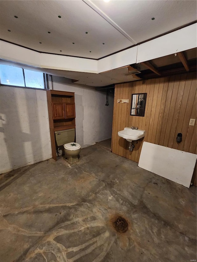 basement with wood walls and a sink