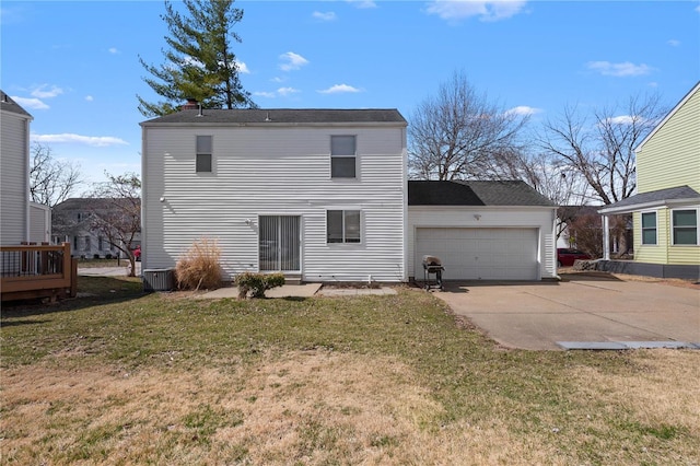 back of property featuring a lawn, driveway, an attached garage, and central AC