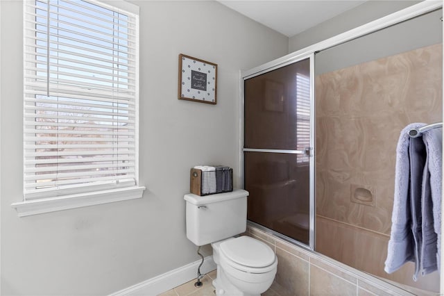 bathroom with a shower with door, baseboards, toilet, and a healthy amount of sunlight