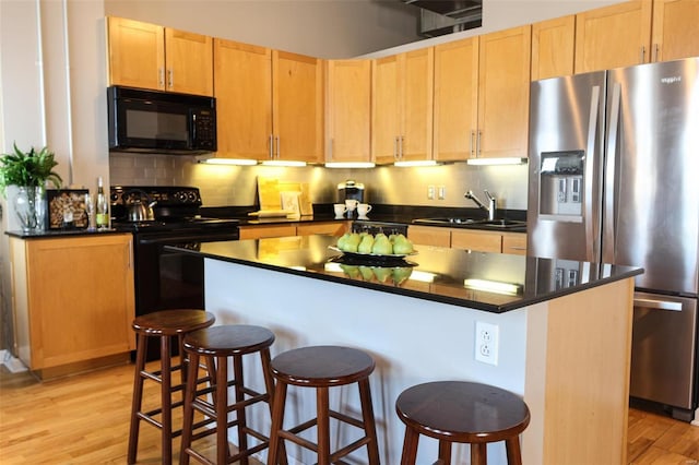 kitchen with light wood-style flooring, a sink, black appliances, tasteful backsplash, and dark countertops