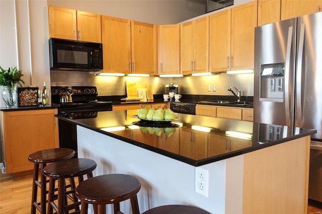 kitchen featuring dark countertops, black appliances, backsplash, and a sink