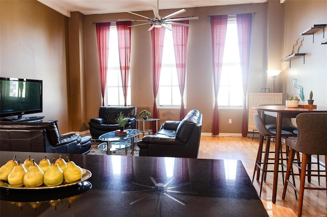 living room with ceiling fan, light wood-style flooring, and baseboards