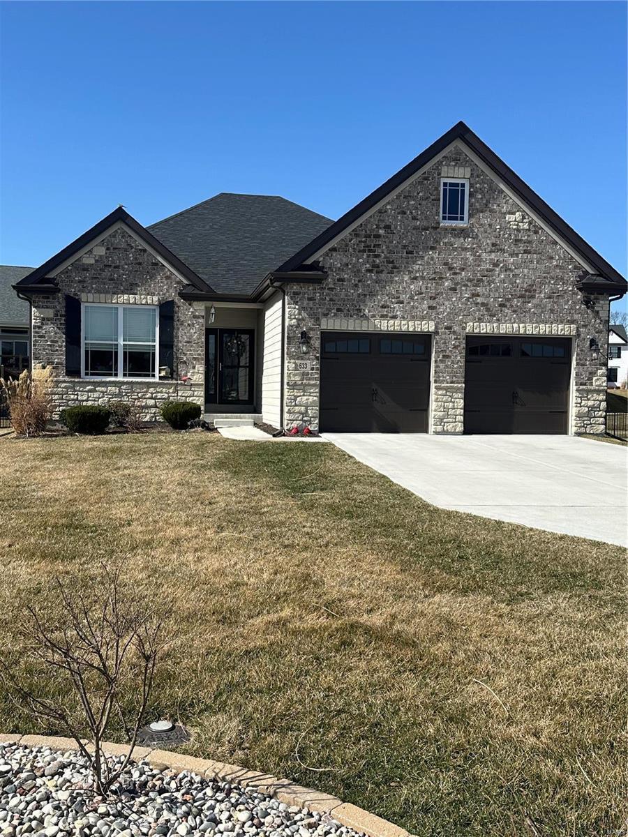 view of front of house featuring a garage, brick siding, driveway, and a front lawn