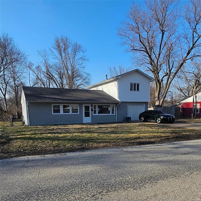 view of front of property featuring driveway, a front lawn, fence, a garage, and brick siding