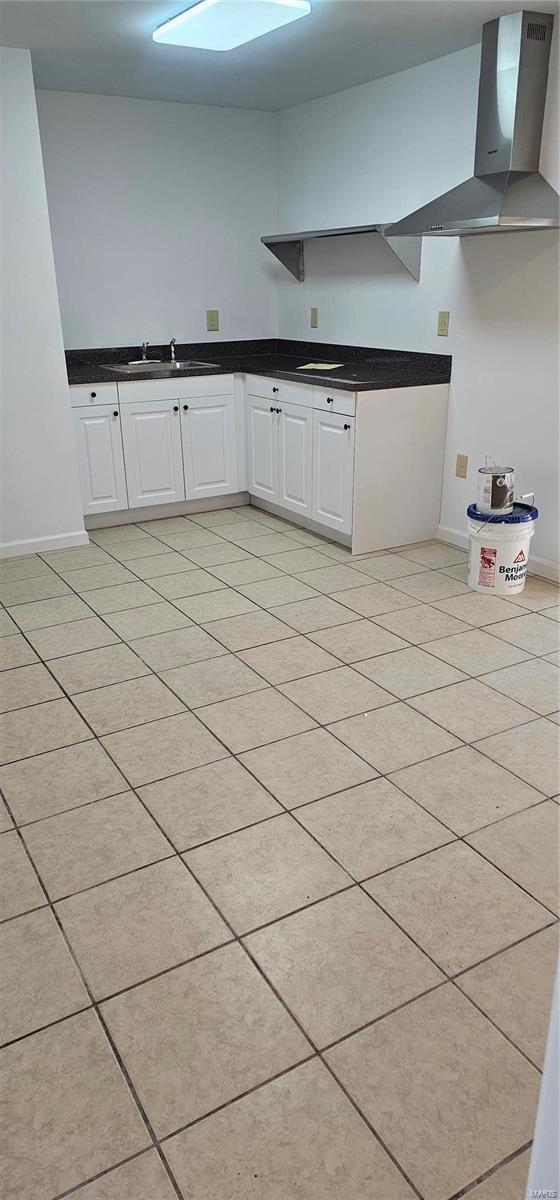 kitchen with dark countertops, white cabinets, baseboards, and a sink