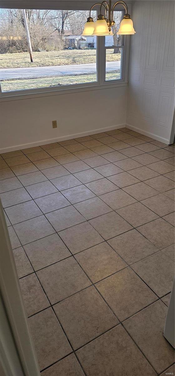 spare room with a notable chandelier and baseboards