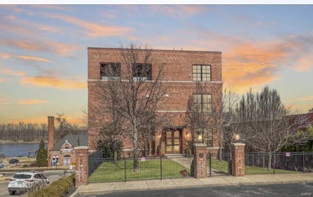 view of front of home featuring a fenced front yard, a front lawn, brick siding, and a water view