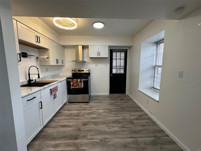 kitchen featuring a sink, stainless steel range with electric cooktop, wall chimney range hood, baseboards, and dark wood-style flooring