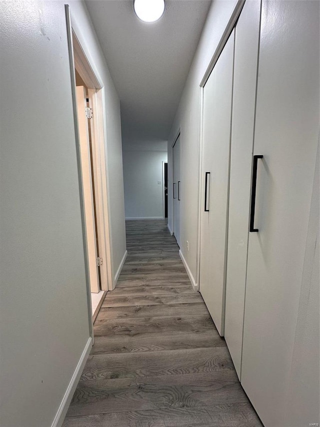 hallway with baseboards and wood finished floors