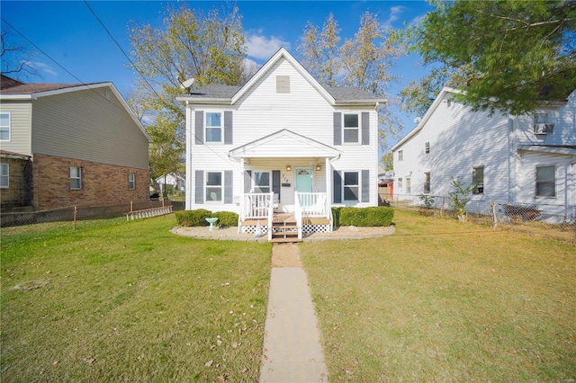 colonial home featuring a porch, a front yard, and fence