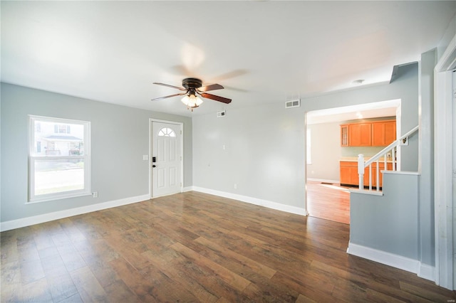 interior space featuring stairway, visible vents, dark wood-type flooring, and baseboards