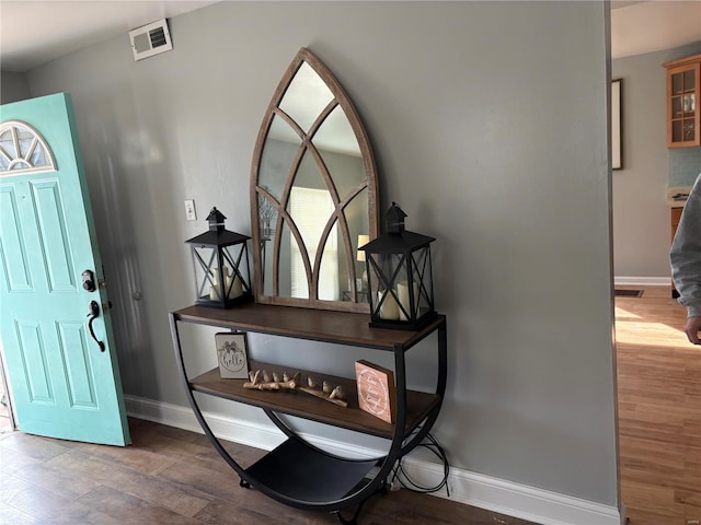 foyer featuring visible vents, baseboards, and wood finished floors