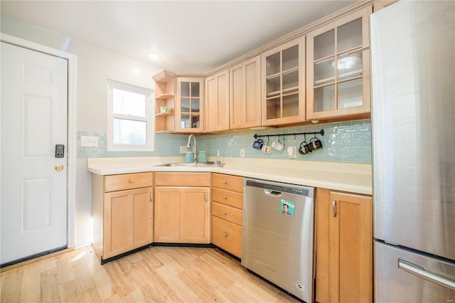 kitchen with decorative backsplash, light brown cabinetry, appliances with stainless steel finishes, and a sink