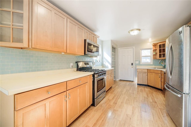 kitchen featuring light wood-type flooring, light brown cabinetry, a sink, appliances with stainless steel finishes, and light countertops