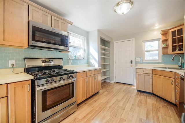 kitchen with plenty of natural light, stainless steel appliances, light wood-style floors, and a sink