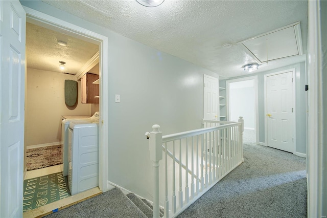 corridor with carpet floors, attic access, a textured ceiling, washer and dryer, and an upstairs landing