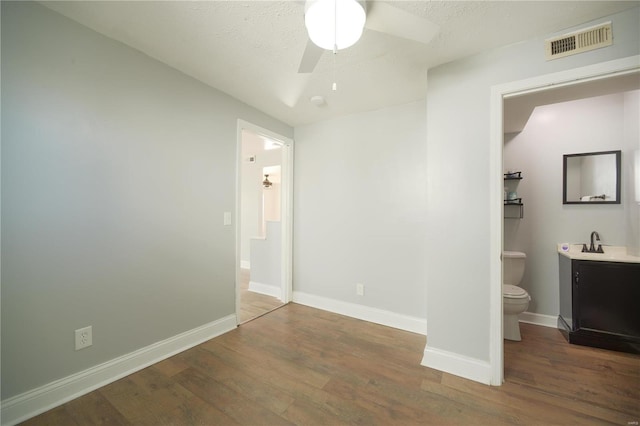 unfurnished bedroom with baseboards, wood finished floors, visible vents, and a sink