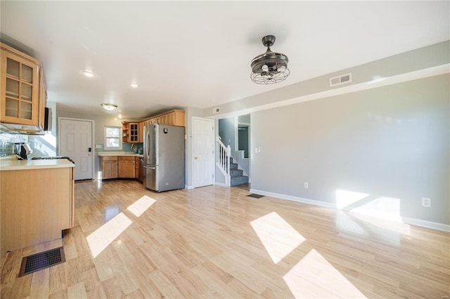 kitchen featuring glass insert cabinets, visible vents, freestanding refrigerator, and light wood-type flooring