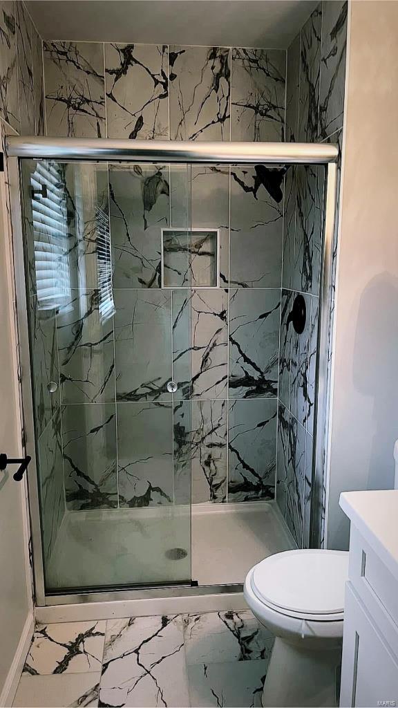 bathroom with a marble finish shower, marble finish floor, and toilet