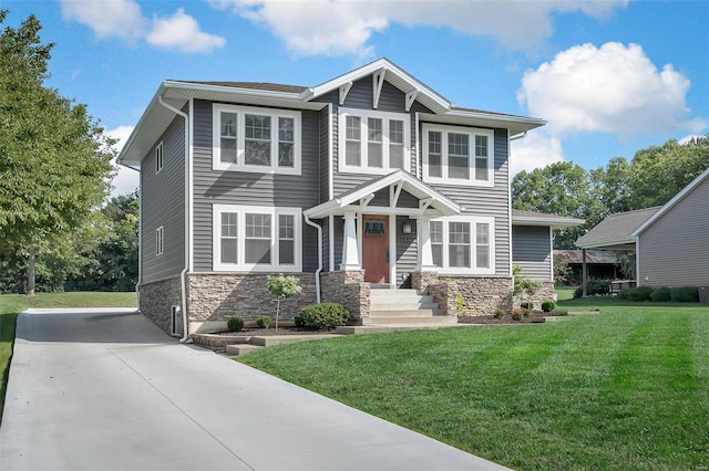 craftsman house featuring a front yard, stone siding, and driveway