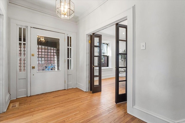 foyer featuring an inviting chandelier, visible vents, light wood-type flooring, and ornamental molding