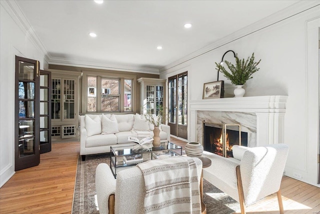 living room with light wood-style flooring, recessed lighting, a fireplace, and ornamental molding