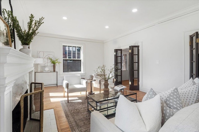 living room with wood finished floors, baseboards, recessed lighting, a fireplace, and ornamental molding