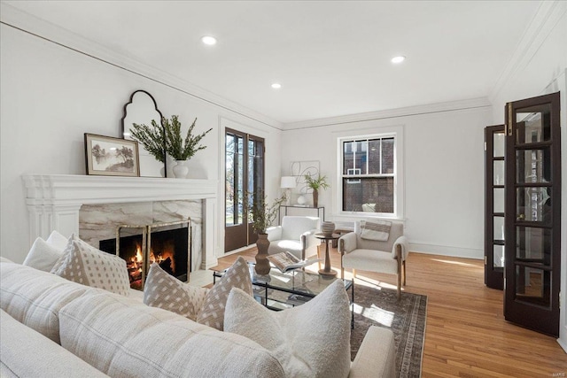 living room with baseboards, wood finished floors, ornamental molding, and a high end fireplace