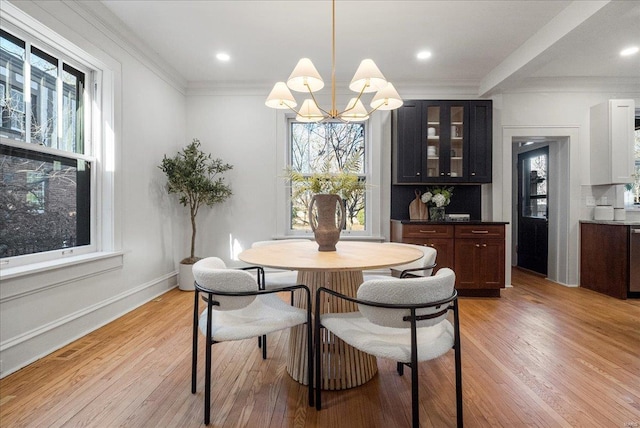 dining space with crown molding, a notable chandelier, light wood finished floors, and a wealth of natural light