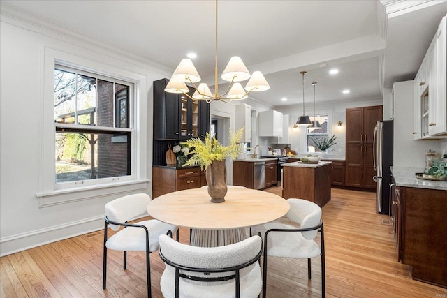 dining area featuring recessed lighting, a notable chandelier, light wood-style floors, and crown molding