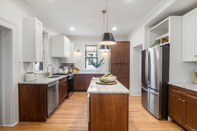 kitchen with a sink, light wood-style flooring, a kitchen island, and stainless steel appliances