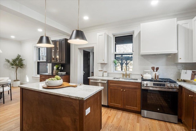 kitchen featuring light stone counters, light wood-style flooring, a sink, appliances with stainless steel finishes, and backsplash