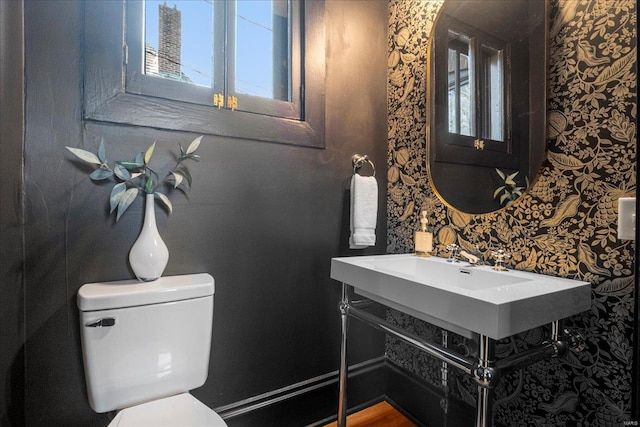 half bathroom with wallpapered walls and toilet