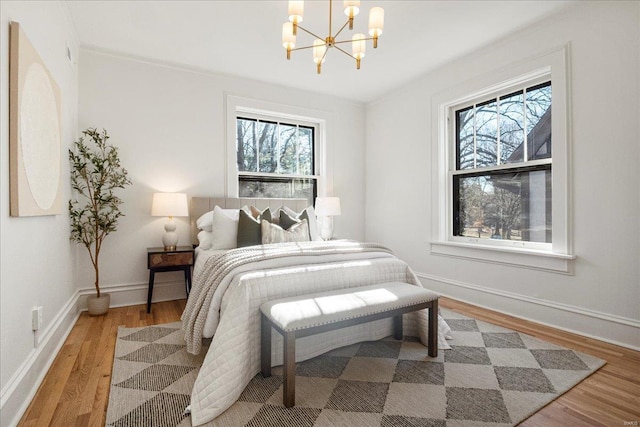 bedroom with light wood-style flooring, a notable chandelier, visible vents, and baseboards