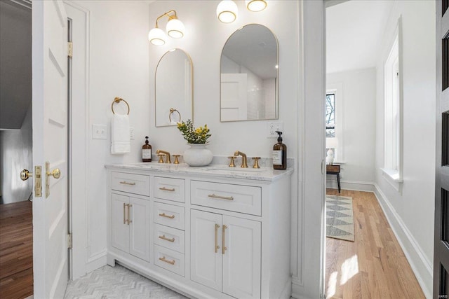 bathroom featuring double vanity, a sink, baseboards, and wood finished floors