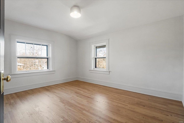 empty room featuring light wood-type flooring, baseboards, and a healthy amount of sunlight