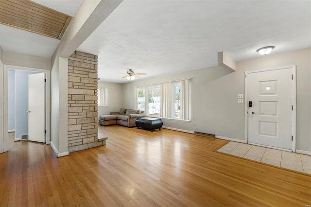 unfurnished living room with a ceiling fan, hardwood / wood-style flooring, and baseboards