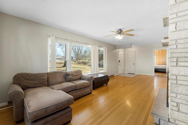 living area with a ceiling fan, light wood-style flooring, and baseboards