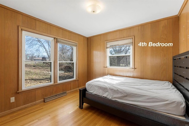 bedroom with light wood-type flooring, visible vents, and wood walls