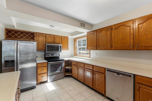 kitchen with visible vents, appliances with stainless steel finishes, brown cabinetry, and light countertops