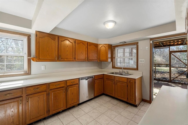 kitchen featuring brown cabinetry, light countertops, a sink, and stainless steel dishwasher