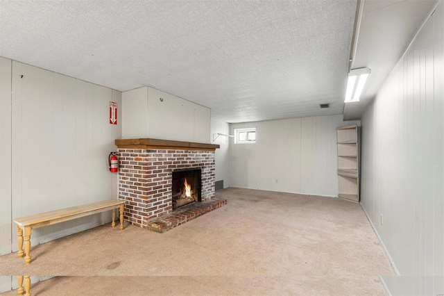 unfurnished living room with visible vents, a brick fireplace, carpet flooring, and a textured ceiling