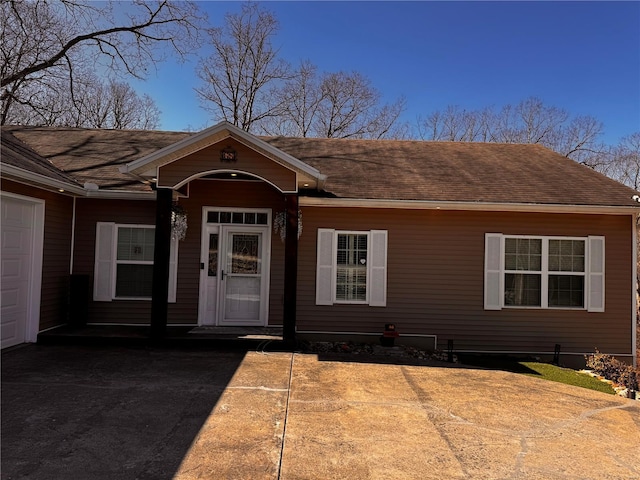 entrance to property featuring roof with shingles and an attached garage