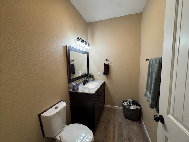 bathroom featuring baseboards, vanity, toilet, and wood finished floors