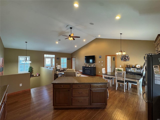 kitchen with ceiling fan with notable chandelier, dark wood-style flooring, vaulted ceiling, freestanding refrigerator, and a center island