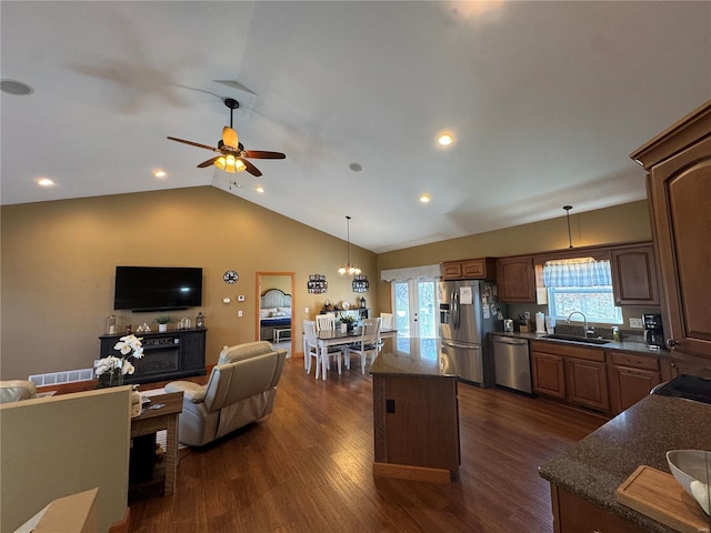 kitchen featuring dark wood finished floors, a kitchen island, open floor plan, stainless steel appliances, and a sink