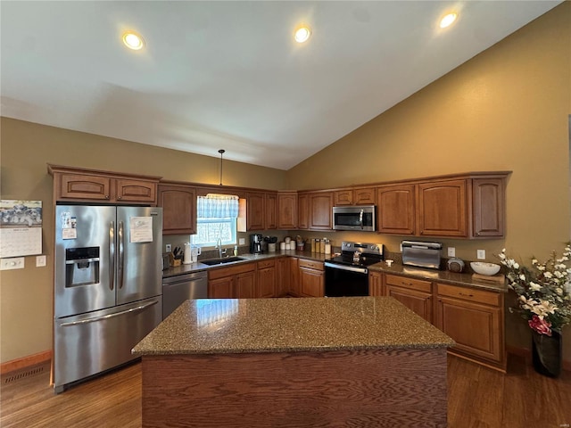 kitchen with stainless steel appliances, dark stone countertops, a sink, and dark wood finished floors