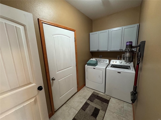 laundry area featuring washer and dryer, cabinet space, and light tile patterned flooring