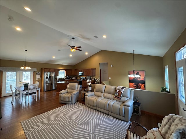 living room with ceiling fan with notable chandelier, high vaulted ceiling, and dark wood-style flooring