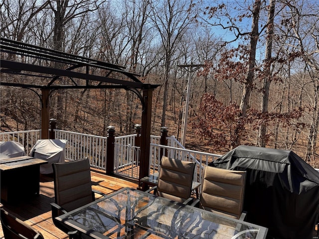 wooden terrace featuring outdoor dining area, grilling area, and a pergola